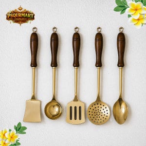 Könnte beinhalten: Ein Set aus fünf Küchenutensilien mit goldfarbenen Metallköpfen und dunkelbraunen Holzgriffen. Das Set enthält einen flachen Pfannenwender, eine geschlossene Schöpfkelle, einen Schlitzwender mit drei Schlitzen, einen Schaumlöffel und einen Löffel.