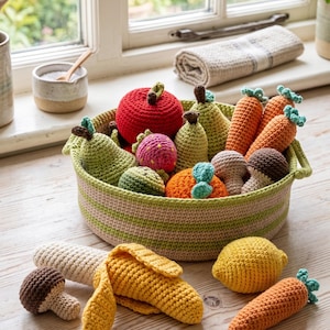 Op de afbeelding: Een gehaakte mand vol kleurrijke, handgemaakte groenten. De mand bevat een rode appel, groene peren, oranje wortelen en andere producten. Extra gehaakte groenten, waaronder een maïskolf en een citroen, liggen rond de mand.