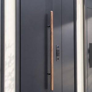 May include: A matte charcoal gray double door featuring a long, cylindrical wooden handle mounted vertically. The door surface includes a series of thin, vertical grooves and an integrated electronic keypad lock system with a circular display.