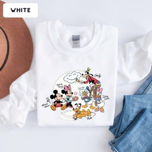 May include: White sweatshirt featuring a colorful graphic of Disney characters, including Mickey Mouse, Minnie Mouse, Donald Duck, Daisy Duck, Goofy, and Pluto. The word "WHITE" is in a white rectangle in the top left corner.