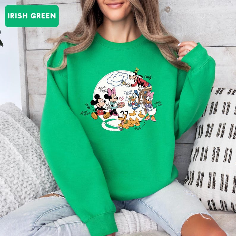 May include: Irish green sweatshirt featuring a graphic of Mickey Mouse, Minnie Mouse, Donald Duck, Daisy Duck, Goofy, and Pluto. The characters are arranged around a white cloud with hearts. The text "Irish Green" is in a green rectangle.