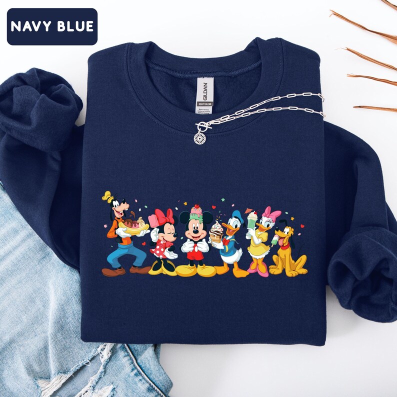 May include: A navy blue crewneck sweatshirt featuring a graphic print of Goofy, Minnie Mouse, Mickey Mouse, Donald Duck, Daisy Duck, and Pluto holding various ice cream treats. The text NAVY BLUE appears in a small box in the top left corner.