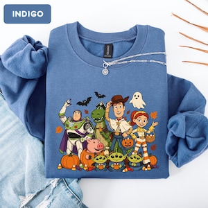 Puede incluir: Una sudadera de cuello redondo color &iacute;ndigo con un estampado gr&aacute;fico de personajes de Toy Story disfrazados para Halloween, incluyendo a Buzz Lightyear, Rex, Woody, Jessie, Hamm y tres alien&iacute;genas, rodeados de calabazas, murci&eacute;lagos, un fantasma y hojas de oto&ntilde;o.