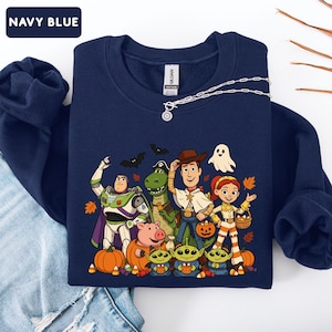 Puede incluir: Una sudadera azul marino de cuello redondo con un estampado gr&aacute;fico de personajes de Toy Story disfrazados para Halloween. El dise&ntilde;o incluye a Buzz Lightyear, Rex, Woody, Jessie, Hamm y tres alien&iacute;genas rodeados de calabazas y hojas de oto&ntilde;o.