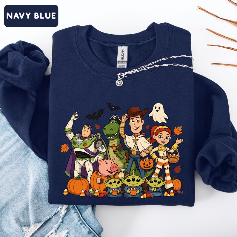 Puede incluir: Una sudadera azul marino de cuello redondo con un estampado gr&aacute;fico de personajes de Toy Story disfrazados para Halloween. El dise&ntilde;o incluye a Buzz Lightyear, Rex, Woody, Jessie, Hamm y tres alien&iacute;genas rodeados de calabazas y hojas de oto&ntilde;o.