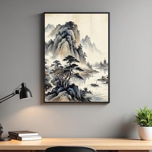 May include: Framed landscape art print depicting a traditional Asian mountain scene. The artwork features a river, trees, and mountains in shades of gray, brown, and white. The print is displayed in a black frame, suitable for home or office decor.