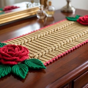 May include: A handmade table runner featuring a central woven design in tan, framed by a pink border. Adorning each end are large, vibrant red rose appliqués with green leaves, adding a touch of floral elegance to the home decor.