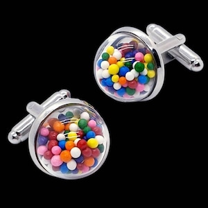 May include: A pair of silver cufflinks with a clear, round face filled with colorful, small spheres. The spheres are various colors, including red, yellow, blue, green, and orange. The cufflinks have a classic, T-bar closure.