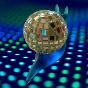 May include: A whimsical sculpture of a disco ball snail. The snail's shell is a mirrored disco ball, reflecting various colors. The snail's body is a translucent blue, set against a dark blue background with a pattern of blue and green dots.