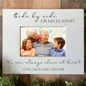 May include: White wooden picture frame with a photo of a family of four. The frame has the text "Side by side or miles apart, we are always close at heart. Love, Jack and Taylor."