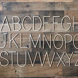 May include: Wooden alphabet letters in a simple, modern font. The letters are arranged in alphabetical order on a wood background.