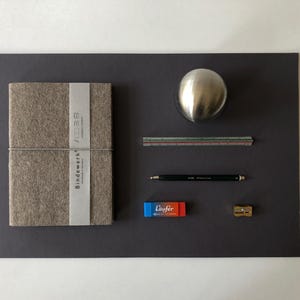 Op de afbeelding: Een witte keramische mok met een zwart handvat en de tekst "But First, Coffee" in een vetgedrukte, zwarte letter. De mok staat op een wit oppervlak, wat het strakke ontwerp benadrukt.