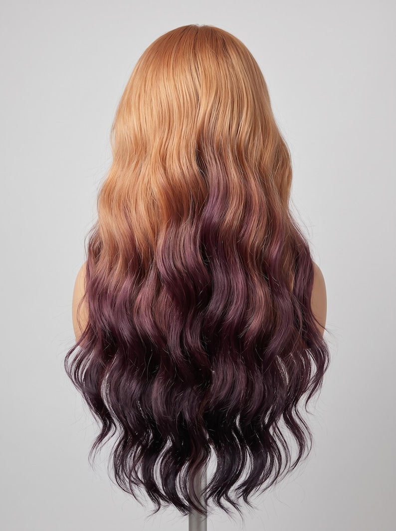 May include: A long, wavy wig featuring a two-tone color gradient. The top section is a warm, light golden-brown shade that transitions into a deep, dark plum purple color at the ends. The hair has a soft, flowing texture with loose, voluminous waves.