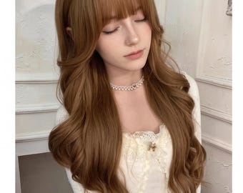 Könnte beinhalten: Eine lange, gewellte, hellbraune Perücke mit geradem Pony. Das Haar hat weiche, voluminöse Locken, die über die Schultern fallen. Eine weiße Perlenhalskette mit einem kleinen Herzanhänger wird um den Hals getragen, kombiniert mit einem weißen Oberteil.
