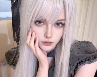Könnte beinhalten: Eine lange, glatte, platinweiße Perücke mit Pony, kombiniert mit einem schwarzen, mit Metallnieten besetzten Lederarmband und einem dunkelgrauen, gepunkteten Kleid mit kurzen Puffärmeln und einem schwarzen Spitzen-Haaraccessoire.