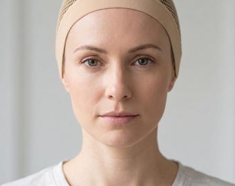 Könnte beinhalten: Eine beige Perückenkappe mit einer feinen Netzstruktur am Oberkopf und einem festen, glatten Gummiband am Rand. Die Kappe ist so konzipiert, dass sie eng am Kopf anliegt und eine sichere Basis für das Styling oder das Tragen von Perücken bietet.