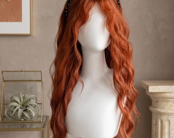 May include: A long, wavy, copper-colored wig styled with a center part and a black headband featuring a white polka dot pattern. The wig is displayed on a white mannequin head, showcasing vibrant orange-red hair with loose, flowing curls.