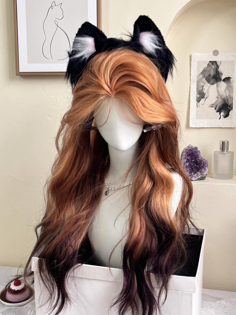 May include: A long, wavy wig featuring a gradient of ginger and copper tones transitioning into dark brown at the ends. The wig is styled with a center part and is adorned with a pair of black and white faux fur cat ears on a headband.