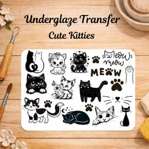 Op de afbeelding: Een rechthoekig vel met onderglazuurtransfers met zwart-witte illustraties van diverse kittens, pootafdrukken en de tekst "Underglaze Transfer Cute Kitties" en "meow". Het vel bevat meerdere kattenhoudingen, bloemelementen en snorharen.