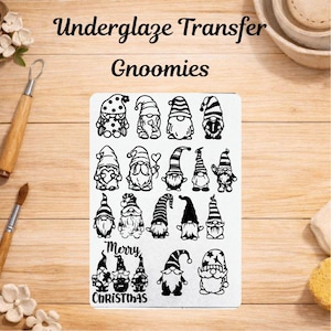 Op de afbeelding: Een rechthoekig vel met zwarte onderglazuur transferontwerpen van diverse kabouters met verschillende mutsen en patronen, inclusief de tekst "Underglaze Transfer Gnoomies" en "Merry Christmas" gedrukt in een zwart schreeflettertype.