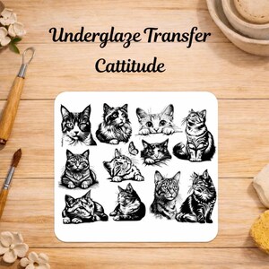 Op de afbeelding: Een wit vierkant vel met zwarte inktillustraties van diverse katten in verschillende houdingen. De tekst "Underglaze Transfer Cattitude" is in het zwart boven de kattenontwerpen op een houten ondergrond gedrukt.