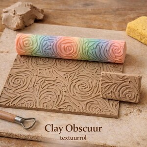 Op de afbeelding: Een cilindrische kleiroller met een pastelkleurig regenboogverloop en een verhoogd rozen- en wervelpatroon. Het wordt getoond met een platte, rechthoekige kleiplaat met hetzelfde reliëfpatroon en een klein kleigereedschap met een metalen lus.