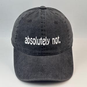 May include: A charcoal grey baseball cap with a washed, distressed finish. The front of the cap features the text "absolutely not." embroidered in white, lowercase, sans-serif letters. The hat has a structured crown and a curved brim.