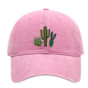 May include: A light pink baseball cap featuring an embroidered design of three green cacti on the front panel. The cap has a structured crown, a curved brim, and a button at the top centre, showcasing a classic six-panel construction style.