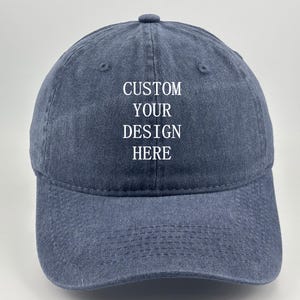 Könnte beinhalten: Eine blaue Baseballkappe aus Denim mit sechs Paneelen und einem gebogenen Schirm. Auf der Vorderseite der Kappe befindet sich der weiß gestickte Text CUSTOM YOUR DESIGN HERE mittig auf der Krone, mit Belüftungsösen an jedem Paneel.