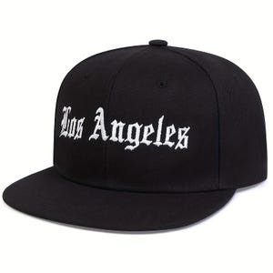 May include: A black baseball cap with a flat brim and a structured crown. The front of the cap features the text Los Angeles embroidered in white using a gothic-style font. The cap includes a small button at the top center and ventilation eyelets.