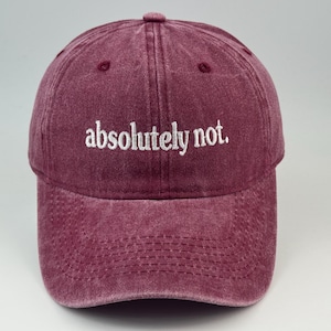 Può includere: Un cappellino da baseball bordeaux con una finitura slavata in stile vintage. La parte anteriore del cappellino presenta il testo "absolutely not." ricamato in lettere bianche minuscole in stile serif. Ha una visiera curva e una corona strutturata.