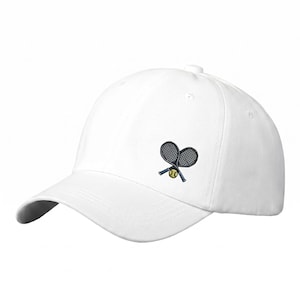 Peut inclure: Une casquette de baseball blanche avec un motif brodé sur le panneau avant. Le design représente deux raquettes de tennis noires croisées avec une balle de tennis jaune placée au centre, là où les manches des raquettes se croisent.