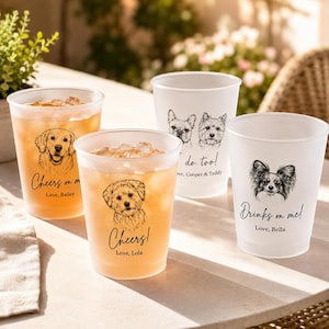 May include: Four frosted plastic cups featuring black line-art illustrations of dog faces. Two cups contain amber-colored liquid with ice. Text includes Cheers on me, Love, Bailey; Cheers!, Love, Lola; do too!, Cooper & Teddy; and Drinks on me!, Love, Bella.