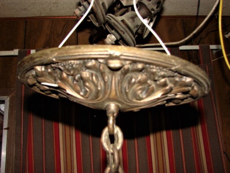 May include: A vintage brass ceiling light fixture with an ornate, detailed design. The fixture has a chain hanging from it and is ready to be installed.
