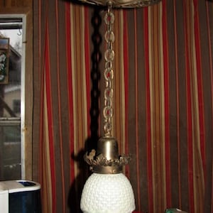 May include: A vintage brass ceiling light fixture with a white frosted glass shade. The fixture has a decorative chain and a detailed brass canopy.