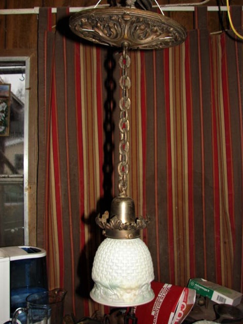 May include: A vintage brass ceiling light fixture with a white frosted glass shade. The fixture has a decorative chain and a detailed brass canopy.