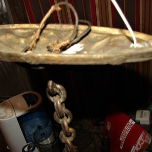 May include: A brass ceiling light fixture with a chain hanging from it. The fixture has a round, decorative top and a white cord.