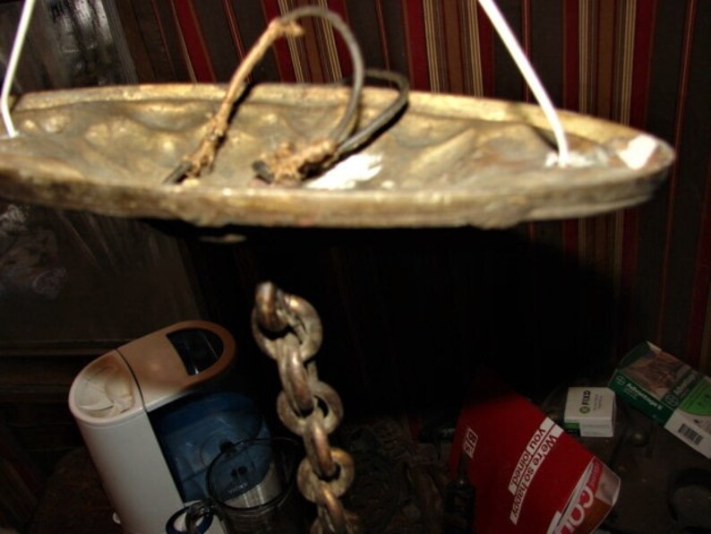 May include: A brass ceiling light fixture with a chain hanging from it. The fixture has a round, decorative top and a white cord.
