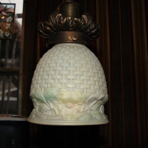 May include: A white glass ceiling light fixture with a woven pattern and floral accents. The fixture has a brass base and a decorative metal trim.