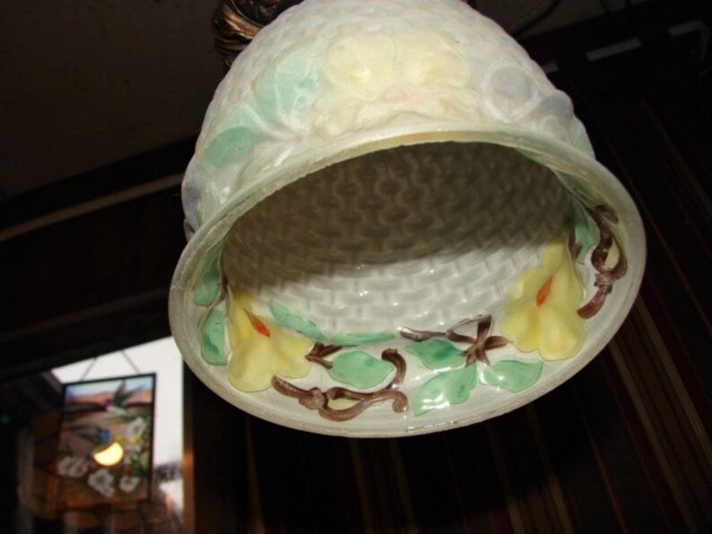 May include: A white glass lampshade with a woven pattern and floral designs in shades of green, yellow, and brown. The lampshade has a scalloped edge and a delicate, feminine aesthetic.