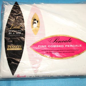 May include: A white double bed sheet in clear plastic packaging. The label features a black oval with the text 1 sheet, double bed, 81 x 108, Penney's, and a pink oval with the text Pencale, Fine Combed Percale, and thread count details.