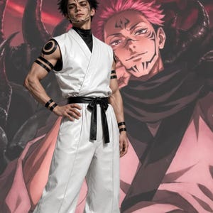 Peut inclure: Un haut de kimono blanc sans manches et un pantalon large assorti avec un col montant noir et une ceinture noire. La tenue comprend des brassards noirs avec des motifs circulaires et linéaires, portés par une personne avec des marques faciales.