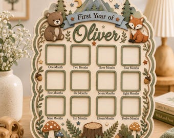 May include: A wooden milestone board titled First Year of Oliver with twelve square photo frames labeled from One Month to Twelve Months. The board features layered cutouts of a bear, a fox, pine trees, mountains, mushrooms, and acorns.