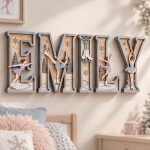 Op de afbeelding: Een houten wandbord dat de naam EMILY spelt in grote blokletters. Elke letter bevat een gelaagd wintertafereel met kunstschaatsers in lavendelkleurige jurken, dennenbomen, sneeuwvlokken en een paar hangende schaatsen in de letter I.