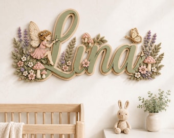 May include: A wall-mounted wooden sign displaying the name Lina in large, sage green cursive letters. The design features a fairy, small mushrooms, a butterfly, and clusters of lavender and pink flowers arranged around the lettering.