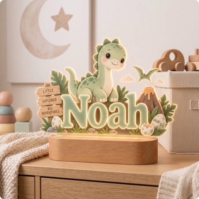Puede incluir: Un letrero luminoso de acr&iacute;lico con un dinosaurio verde de dibujos animados, un volc&aacute;n y huevos. El nombre Noah aparece en letras grandes de color verde claro. Un poste de madera dice Little Explorer Big Adventures. La pieza descansa sobre una base de madera.