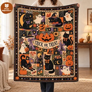 Op de afbeelding: Een rechthoekige plaid met een Halloween-patchworkontwerp met zwarte katten, spoken, pompoenen en een centrale banner met de tekst TRICK OR TREAT. Het patroon bevat herfstbladeren, sterren en spinnenwebben in oranje, paars en zwart.