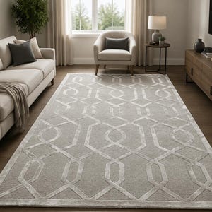 May include: A rectangular area rug featuring a light grey background with a repeating white geometric pattern of interlocking hexagons and lines. The rug has a low-pile texture and a finished border, covering the floor in a living room space.