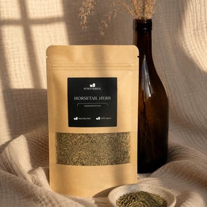 Puede incluir: Una bolsa beige resellable que contiene hierba de cola de caballo seca, etiquetada con el texto Soma Herbal, Horsetail Herb, Equisetum arvense, Naturally dried y 100% organic. Un pequeño cuenco de cerámica con la hierba se sitúa delante.