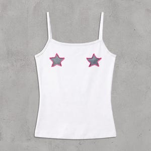 Può includere: Canotta bianca con spalline sottili e due applicazioni a forma di stella grigia bordate di rosa. Il top è uno stile semplice e casual, adatto per essere indossato a strati o con il caldo. Il capo è realizzato in tessuto morbido e leggero.